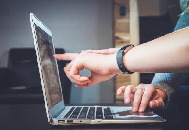Person pointing at a report on a laptop screen.